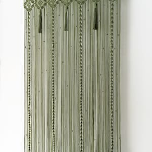 Symmetrical long macrame hanging in a trendy forest-inspired olive green colorway.