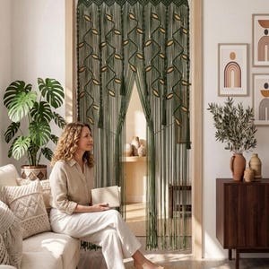 Forest green cotton cord macrame curtain with floor-length fringe and tassel accents hanging on a white wall