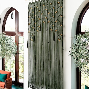 Decorative dark green fiber art tapestry with a symmetrical botanical vine layout.