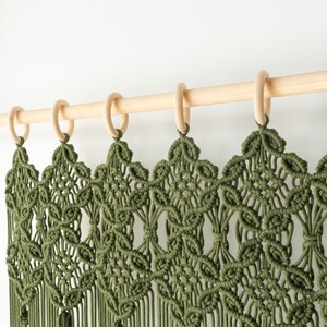 Close-up of the artisanal knotted header on a dark olive green macrame door hanging.