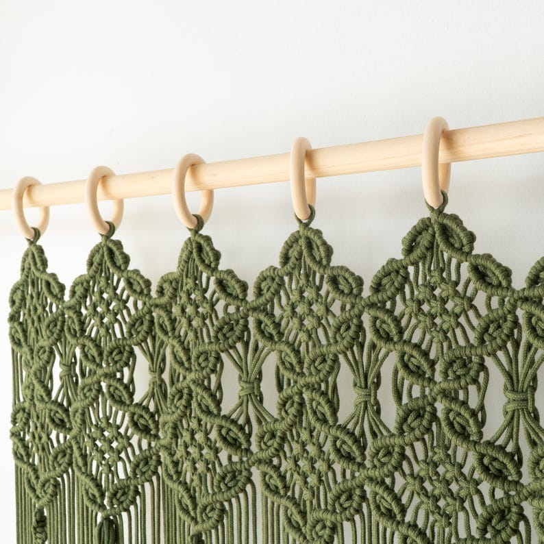 Close-up of the artisanal knotted header on a dark olive green macrame door hanging.