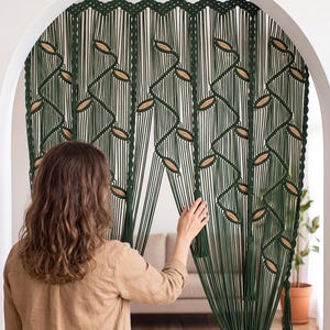 Deep green hand-knotted macrame backdrop tapestry featuring geometric vine lattice patterns and tassel details