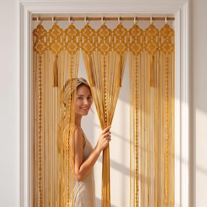 May include: A mustard yellow macrame door curtain featuring an intricate knotted geometric valance at the top, hanging from a wooden rod with white rings. The curtain consists of long vertical cords, decorative knotted sections, and tassels.