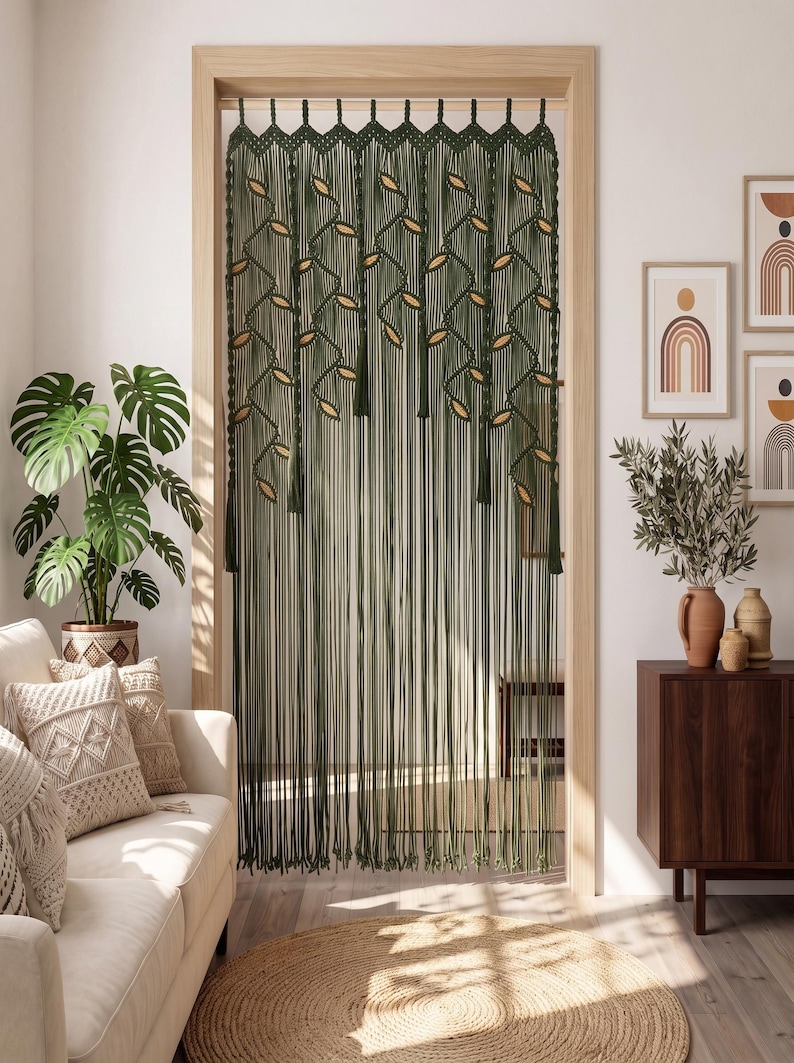 Large dark forest green macrame doorway curtain with subtle yellow leaf accents suspended on a wooden rod
