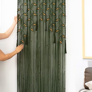 Hand-woven dark green macrame hanging with delicate almond-shaped latte accents.