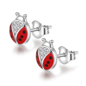 May include: A pair of silver ladybird stud earrings. Each earring features a red enamel body with black spots and a clear crystal-studded head. The earrings have a post and butterfly backing.