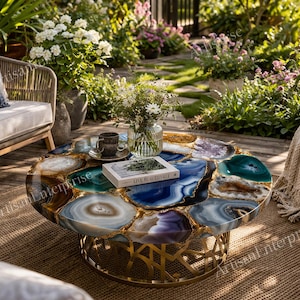 Può includere: Un tavolino rotondo dal design unico. Il piano è realizzato con fette di agata lucidata nei toni del blu, verde e viola, con dettagli dorati. Il tavolo ha una base in metallo dorato. Un libro e una tazza sono sul tavolo.