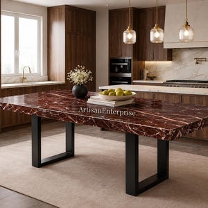 Puede incluir: Una mesa de comedor rectangular con una encimera de mármol rojo y patas de metal negro. La mesa está en una cocina moderna con gabinetes de madera oscura y una alfombra de color claro. La mesa mide aproximadamente 254 cm de largo.