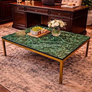 Puede incluir: Mesa de centro rectangular con tapa de mármol verde y patas doradas. La mesa tiene el texto "Artisan Enterprise" en la superficie. Un jarrón con rosas blancas y una bandeja de aperitivos están sobre la mesa.