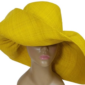 May include: A wide-brimmed, bright yellow sun hat. The hat has a large, gently curved brim and a textured weave. The hat is designed to provide ample shade and is likely made of a natural fiber. The hat is a vibrant accessory.