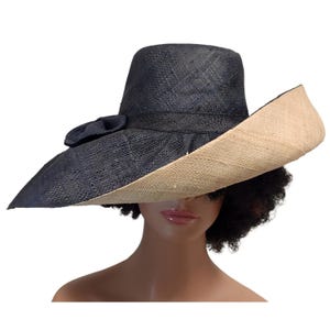 May include: A two-tone wide-brimmed hat. The crown and bow are navy blue, and the brim is a natural beige colour. The hat is made of woven material, ideal for sun protection. The hat's brim is approximately 10 cm wide.