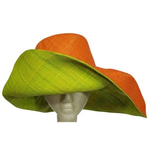 May include: A two-tone sun hat with a wide brim. The crown is a bright orange, while the underside of the brim is lime green. The hat is made from a woven material, giving it a textured look.