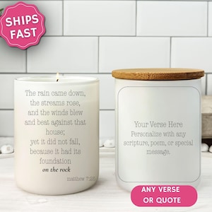 May include: Two white candles with wooden lids. One candle has a lit wick and text from Matthew 7:25. The other candle has space for personalized text. The image includes a pink "Ships Fast" sticker and a pink "Any Verse or Quote" sticker.