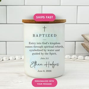 May include: A white candle with a wooden lid, featuring the word "BAPTIZED" and a cross symbol. The candle includes text about spiritual rebirth and personalization details. A pink sticker reads "SHIPS FAST".