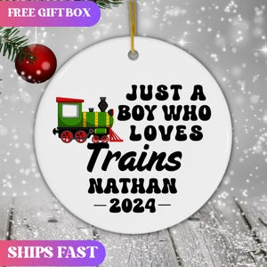 May include: White ceramic ornament with a green and red toy train, the text "Just a boy who loves trains Nathan - 2024" in black.