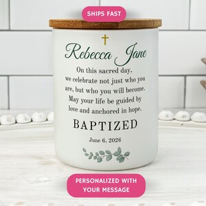 May include: White ceramic candle holder with a bamboo lid. The candle holder is inscribed with the name "Rebecca Jane", a cross, and the word "BAPTIZED". Includes a floral design and the date June 6, 2026.