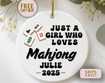 May include: White ceramic ornament with a gold string for hanging. The ornament features the text "JUST A GIRL WHO LOVES Mahjong JULIE -2025-" and Mahjong tiles. Includes a "FREE GIFT BOX" and "SHIPS FAST!" graphic.