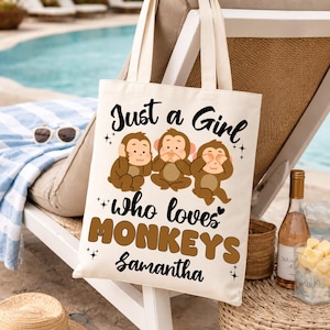 May include: Off-white canvas tote bag with the text "Just a Girl who loves MONKEYS Samantha" and three cartoon monkeys. The monkeys are brown and depicted covering their ears, eyes, and mouth. The bag has two beige handles.
