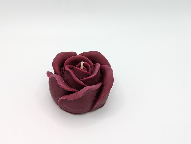 May include: A single burgundy rose-shaped candle with a white wick.