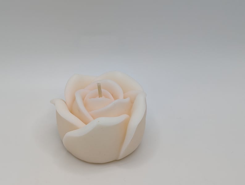 May include: A white rose-shaped candle with a single wick.