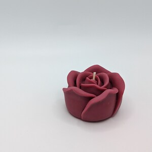 May include: A burgundy rose-shaped candle with a single wick.