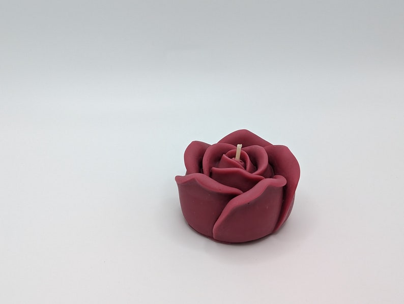 May include: A burgundy rose-shaped candle with a single wick.