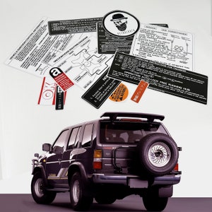 May include: A black Nissan Pathfinder SUV with a spare tyre mounted on the back. The vehicle has a sticker on the rear window that says "Auto-Lock Free Running Hub".