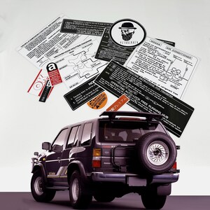 May include: A black Nissan Pathfinder SUV with a spare tyre mounted on the back. The vehicle has a roof rack and a sticker that says "Operating Auto-Lock Free Running Hub".