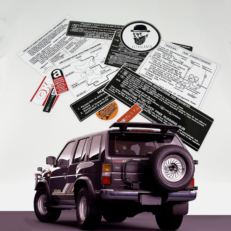 May include: A black Nissan Pathfinder SUV with a spare tyre mounted on the back. The vehicle has a roof rack and a sticker that says "Operating Auto-Lock Free Running Hub".