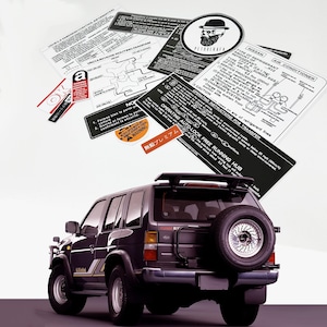 May include: A black Nissan Pathfinder SUV with a spare tyre mounted on the back. The vehicle has a roof rack and a sticker on the back that says "Free Running Hub".