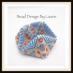 May include: A geometric beaded design in shades of blue, orange, and white. The design features intricate patterns and the text "Bead Design By Laurie". The object is a folded, three-dimensional shape.