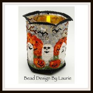 May include: A cylindrical beaded candle holder featuring a Halloween theme with white ghosts, orange jack-o'-lanterns, and black bats against a gray background. The top and bottom edges are trimmed in black beads. Text reads: Bead Design By Laurie.