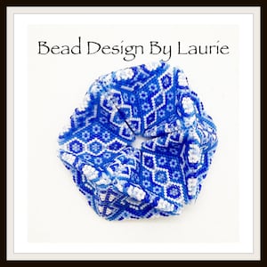 May include: A blue and white patterned scrunchie with the text "Bead Design By Laurie" in black script. The scrunchie features a geometric design in shades of blue and white.