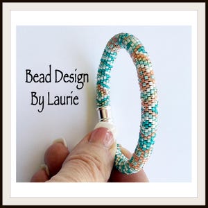 May include: A turquoise, white, and peach beaded bracelet with a silver magnetic clasp. Bead Design By Laurie.