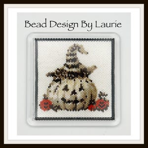 Op de afbeelding: Een vierkante kralenpatch met een jack-o'-lantern die een gestreepte heksenhoed draagt, geflankeerd door twee kleine rode pompoenen. Het ontwerp is gemaakt van witte, zwarte en beige kralen. De tekst Bead Design By Laurie staat erboven.