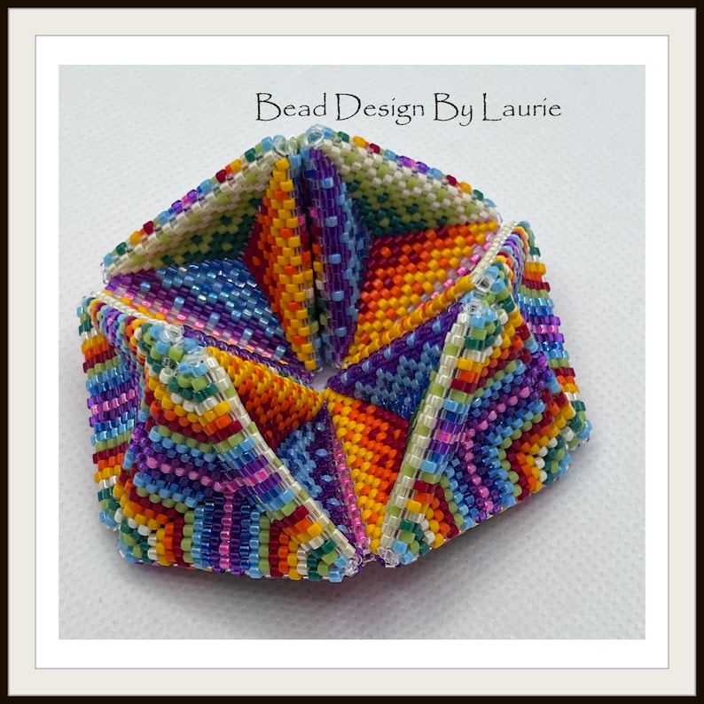 May include: A colorful beaded bracelet made of small, multi-colored beads. The bracelet is made up of six triangular sections that are joined together. The bracelet is a vibrant mix of red, orange, yellow, green, blue, purple, and white beads. The text "Bead Design By Laurie" is visible in the top center of the image.
