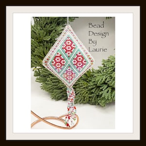 May include: A white, green and red beaded ornament with a tassel. The ornament is shaped like a diamond and features a floral design. The text "Bead Design By Laurie" is visible in the image.