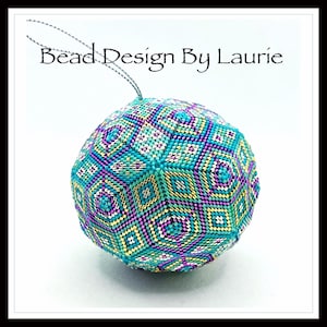 Op de afbeelding: Een ronde, turquoise, paarse, gouden en witte kralenversiering met een geometrisch patroon. De versiering is rond en heeft een lus aan de bovenkant om op te hangen.