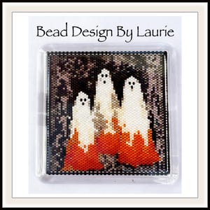 Op de afbeelding: Een kralenkunstwerk met drie witte geesten met oranje en zwarte achtergronden. Het kunstwerk is ingelijst in een transparant plastic frame. De tekst "Bead Design By Laurie" staat bovenaan de afbeelding.