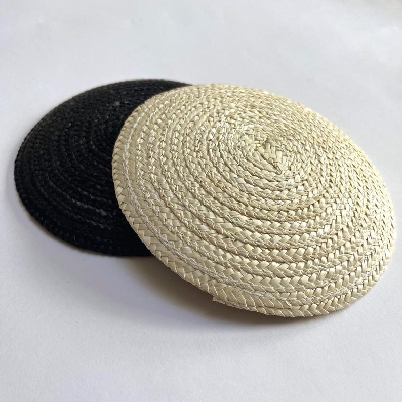 May include: Two round woven placemats. One is black, and the other is a natural beige color. The placemats are made of a tightly woven material, with a spiral pattern radiating from the center. They are suitable for dining and home decor.