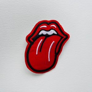 Könnte beinhalten: Gestickter Aufnäher mit dem ikonischen Zungen- und Lippen-Logo der Rolling Stones. Der Aufnäher hat eine rote Zunge mit weißen Akzenten, schwarzen Umrissen und einer weißen Oberlippe. Geeignet für Jacken, Taschen oder andere Textilien.