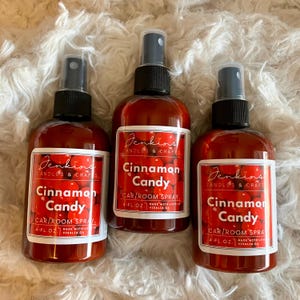 May include: Three 4-ounce bottles of cinnamon candy car and room spray. The bottles are red and have white labels with the text "Jenkins Candles & Crafts" and "Cinnamon Candy" on them.