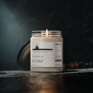 May include: A white ceramic mug with a black handle and the text "But First, Coffee" in a bold, black font. The mug is set against a blurred background, suggesting a cozy setting.