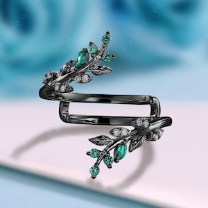 May include: Black ring with a twisted band and a leafy design with green and white stones.