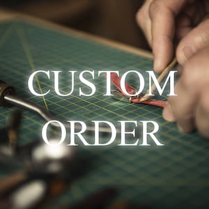 May include: Close-up of a person working on a custom order. The person is using a tool to work on a piece of red leather. The text "CUSTOM ORDER" is superimposed on the image.