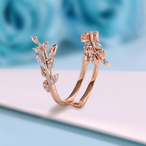 May include: A rose gold ring featuring a delicate design of leaves and small diamonds. The ring is open and has a curved shape.