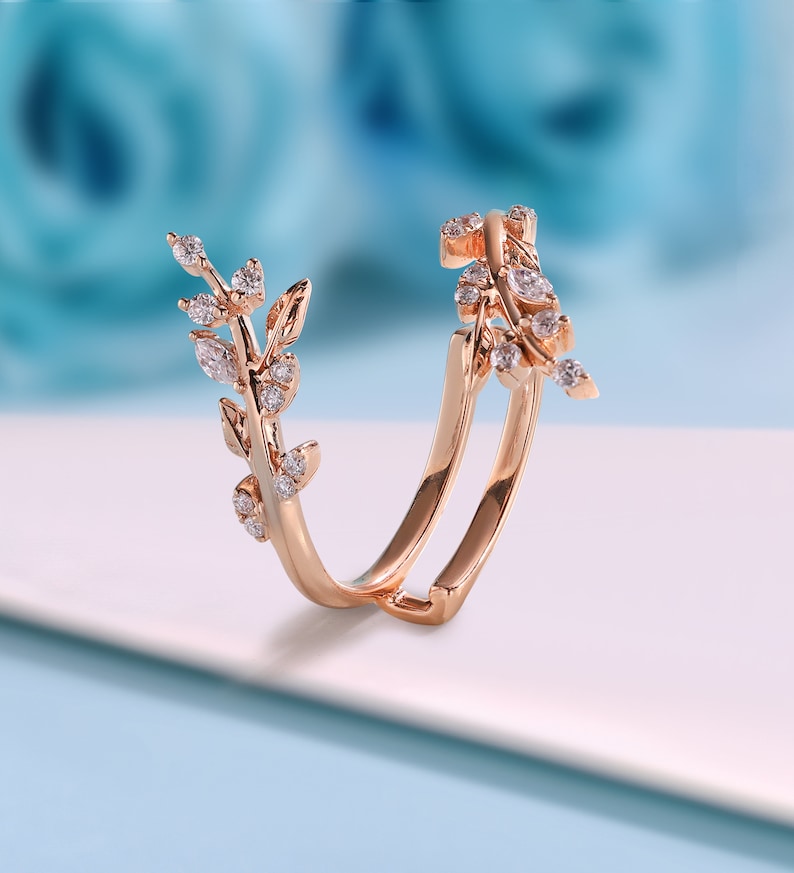 May include: A rose gold ring featuring a delicate design of leaves and small diamonds. The ring is open and has a curved shape.