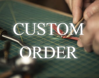 May include: A close-up of a leather crafting project with the words "CUSTOM ORDER" in white. The image shows hands working on a red leather piece with tools on a green grid surface.