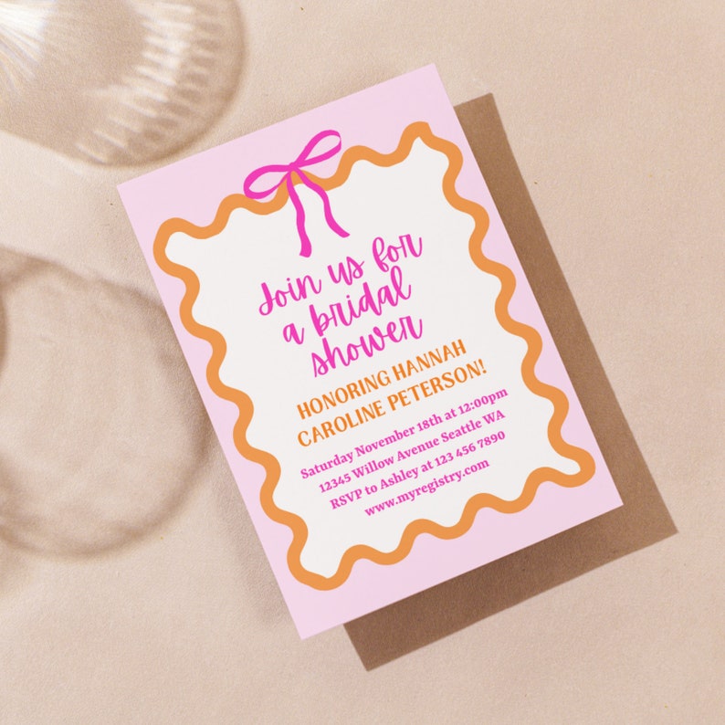 May include: Pink and orange bridal shower invitation with a pink bow at the top. The text reads "Join us for a bridal shower honoring Hannah Caroline Peterson!" with the date, time, location, RSVP information, and website address.