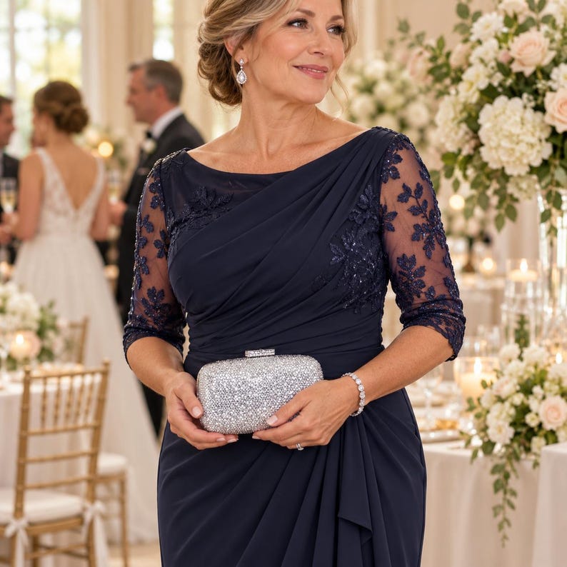 Puede incluir: Un vestido largo de color azul marino con mangas tres cuartos transparentes con bordados florales oscuros, cuerpo drapeado y escote barco, acompa&ntilde;ado de un bolso de mano rectangular con purpurina plateada y cierre met&aacute;lico.